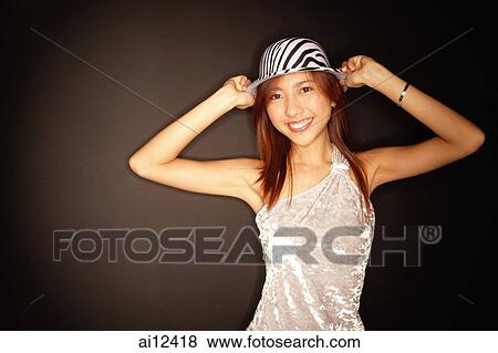 Stock Photo - Young woman with hat, hands on head. Fotosearch