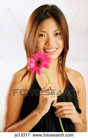 Young woman with single stalk of flower, smiling at camera View Large Photo Image Stock Photo - Young woman with single stalk of flower, smiling at camera. Fotosearch