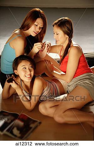 Young women applying nail polish and relaxing together View Large Photo Image Stock Image - Young women applying nail polish and relaxing together. Fotosearch
