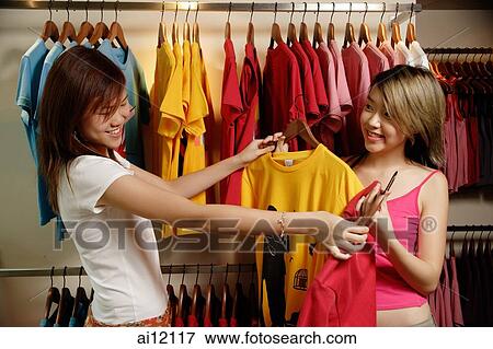 Young women at clothes shop looking at T shirts View Large Photo Image Stock Photo - Young women at clothes shop looking at T shirts. Fotosearch