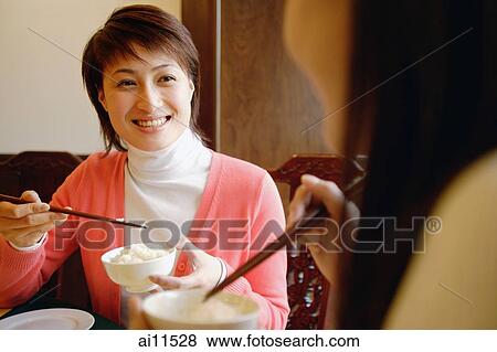Young women eating at a Chinese restaurant, face to face View Large Photo Image Stock Photo - Young women eating at a Chinese restaurant, face to face. Fotosearch