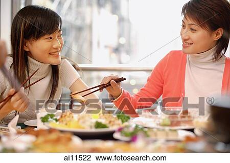 Young women eating at Chinese restaurant, side by side View Large Photo Image Stock Image - Young women eating at Chinese restaurant, side by side. Fotosearch