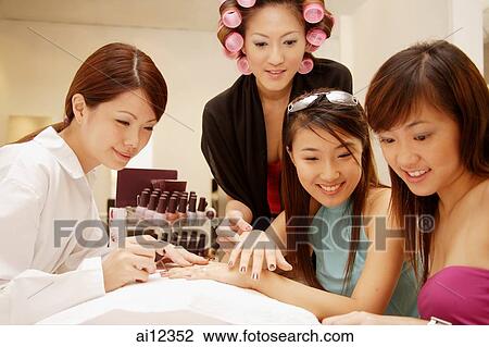 Stock Image - Young women getting a manicure at a beauty salon. Fotosearch