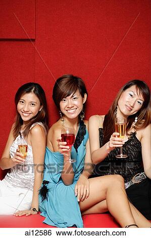 Young women, holding drinks and smiling at camera View Large Photo Image Stock Photograph - Young women, holding drinks and smiling at camera. Fotosearch