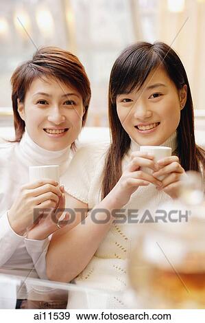Young women holding teacups, looking at camera View Large Photo Image Stock Photo - Young women holding teacups, looking at camera. Fotosearch