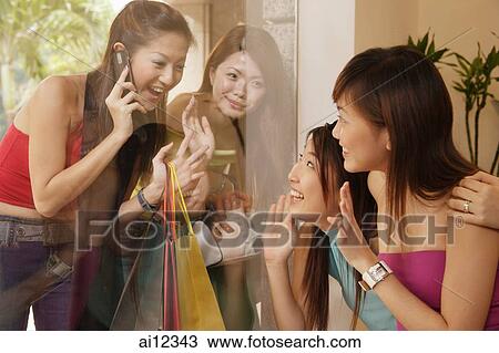 Young women looking at each other through glass window View Large Photo Image Stock Image - Young women looking at each other through glass window. Fotosearch