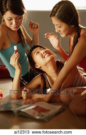 Young women relaxing together at home with nail polish and magazines View Large Photo Image Stock Image - Young women relaxing together at home with nail polish and magazines. Fotosearch