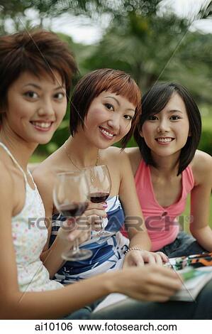 Young women sitting, looking at camera, wine glasses in hand View Large Photo Image Stock Photograph - Young women sitting, looking at camera, wine glasses in hand. Fotosearch
