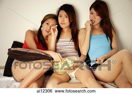 Young women, sitting side by side, eating popcorn View Large Photo Image Stock Photograph - Young women, sitting side by side, eating popcorn. Fotosearch