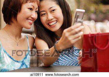 Young women smiling looking at mobile phone View Large Photo Image Stock Image - Young women smiling looking at mobile phone. Fotosearch