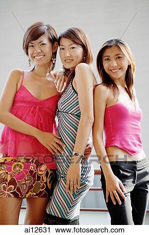 Young women standing side by side, looking at camera View Large Photo Image Stock Image - Young women standing side by side, looking at camera. Fotosearch