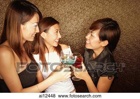 Young women toasting with drinks, looking at each other View Large Photo Image Stock Photo - Young women toasting with drinks, looking at each other. Fotosearch