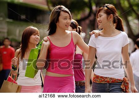 Young women walking side by side, carrying shopping bags View Large Photo Image Stock Photo - Young women walking side by side, carrying shopping bags. Fotosearch