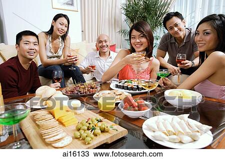Adults having a party in living room, smiling at camera, food on coffee table View Large Photo Image Stock Image - Adults having a party in living room, smiling at camera, food on coffee table. Fotosearch