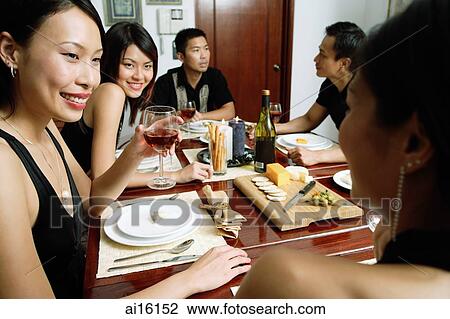 Stock Image - Adults having dinner party, over the shoulder view. Fotosearch