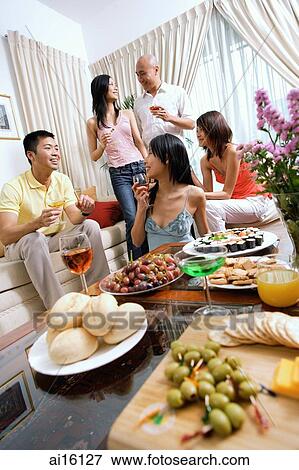 Stock Photo - Adults in living room, having a party, food in the foreground. Fotosearch