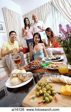 Adults in living room, having a party, smiling at camera, food in the foreground View Large Photo Image Stock Photograph - Adults in living room, having a party, smiling at camera, food in the foreground. Fotosearch