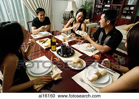Adults sitting around dinner table, woman taking from plate being passed around View Large Photo Image Stock Image - Adults sitting around dinner table, woman taking from plate being passed around. Fotosearch