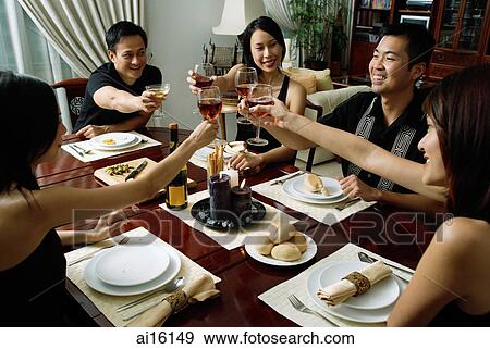 Adults toasting with wine glasses across dining table View Large Photo Image Stock Photo - Adults toasting with wine glasses across dining table. Fotosearch