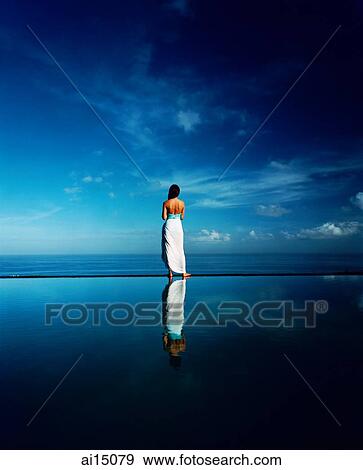 Asian female standing along edge of horizon pool View Large Photo Image Stock Photo - Asian female standing along edge of horizon pool. Fotosearch