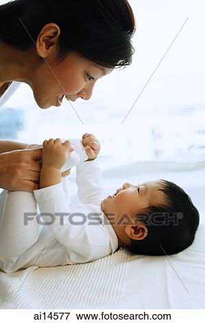 Baby boy lying down, mother holding his feet View Large Photo Image Stock Photo - Baby boy lying down, mother holding his feet. Fotosearch