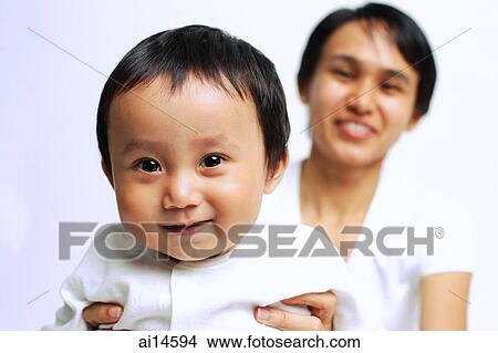 Baby boy smiling at camera, mother carrying him View Large Photo Image Picture - Baby boy smiling at camera, mother carrying him. Fotosearch