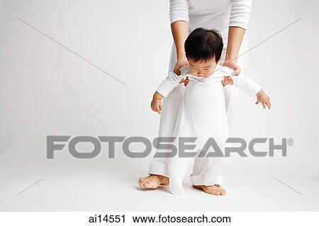 Baby boy standing, being supported by mother from behind View Large Photo Image Stock Image - Baby boy standing, being supported by mother from behind. Fotosearch