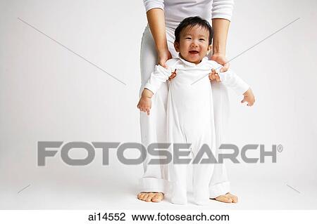 Baby boy standing, looking at camera, mother holding him View Large Photo Image Stock Image - Baby boy standing, looking at camera, mother holding him. Fotosearch