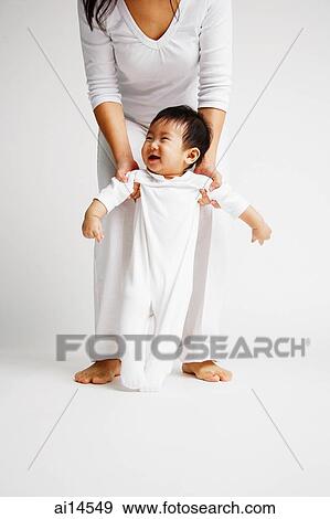Stock Photo - Baby boy standing, mother behind him holding his arms. Fotosearch