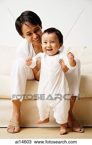 Baby boy standing, mother supporting him View Large Photo Image Stock Image - Baby boy standing, mother supporting him. Fotosearch