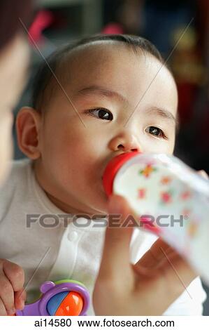 Baby girl drinking from bottle, looking away View Large Photo Image Stock Image - Baby girl drinking from bottle, looking away. Fotosearch
