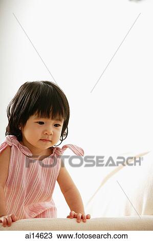 Baby girl leaning on sofa, looking down View Large Photo Image Stock Image - Baby girl leaning on sofa, looking down. Fotosearch
