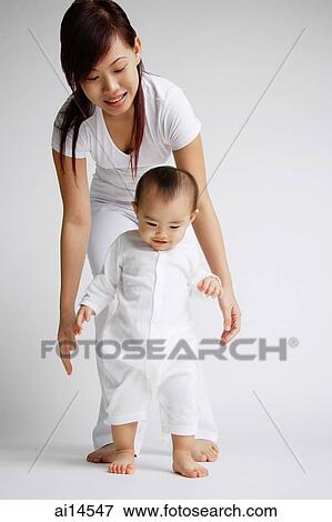 Baby girl standing, mother behind her View Large Photo Image Stock Photo - Baby girl standing, mother behind her. Fotosearch