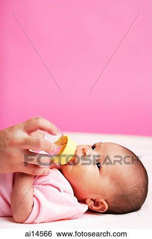 Stock Photograph - Baby lying down, drinking from bottle. Fotosearch