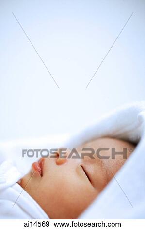 Stock Photo - Baby wrapped in blanket, sleeping, head shot. Fotosearch