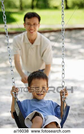 Boy on swing, father pushing him View Large Photo Image Stock Photo - Boy on swing, father pushing him. Fotosearch