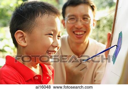 Boy painting on easel, father next to him, smiling View Large Photo Image Stock Photo - Boy painting on easel, father next to him, smiling. Fotosearch