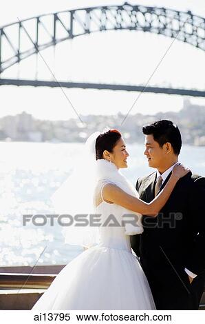 Bride and groom standing face to face, water and bridge behind them View Large Photo Image Stock Photography - Bride and groom standing face to face, water and bridge behind them. Fotosearch