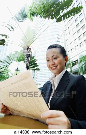 Business woman holding newspaper, smiling View Large Photo Image Stock Photo - Business woman holding newspaper, smiling. Fotosearch