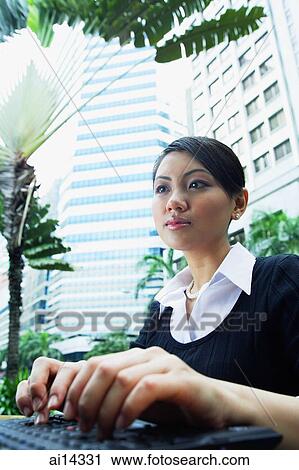 Stock Image - Business woman using laptop, low angle view. Fotosearch