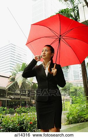 Business woman using mobile phone and carrying red umbrella View Large Photo Image Stock Photograph - Business woman using mobile phone and carrying red umbrella. Fotosearch