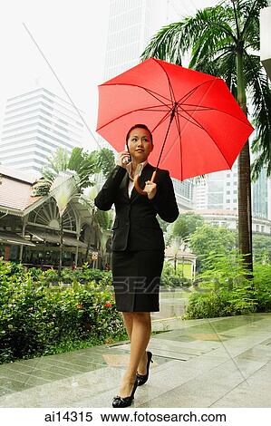 Business woman using mobile phone, holding umbrella View Large Photo Image Stock Photography - Business woman using mobile phone, holding umbrella. Fotosearch