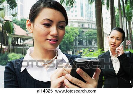 Business woman using PDA, woman in the background on the phone View Large Photo Image Stock Photography - Business woman using PDA, woman in the background on the phone. Fotosearch