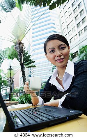 Business woman with laptop, holding coffee cup, smiling at camera View Large Photo Image Picture - Business woman with laptop, holding coffee cup, smiling at camera. Fotosearch