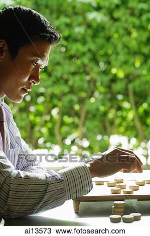 Stock Image - Businessman about to make a move in chess game. Fotosearch