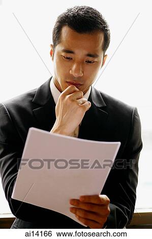 Stock Photograph - Businessman holding document, hand on chin. Fotosearch