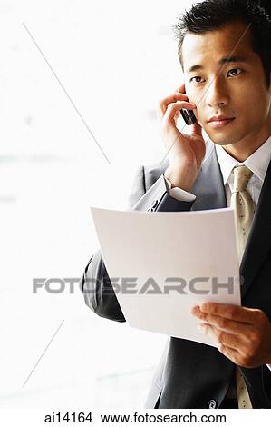 Businessman holding document, using mobile phone, looking away View Large Photo Image Picture - Businessman holding document, using mobile phone, looking away. Fotosearch