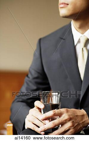 Stock Image - Businessman holding glass of water. Fotosearch