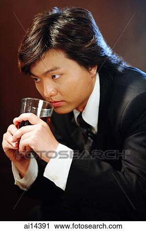 Businessman holding glass of whiskey to his mouth, sideview View Large Photo Image Stock Image - Businessman holding glass of whiskey to his mouth, sideview. Fotosearch