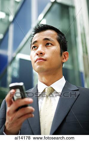 Businessman holding mobile phone, looking away View Large Photo Image Stock Photo - Businessman holding mobile phone, looking away. Fotosearch